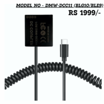 A black USB-C dummy battery (DC Coupler) labeled 'DMW-DCC11' and 'DC COUPLER' in white, connected to a coiled black cable ending in a male USB-C connector. The device is advertised with the text: "MODEL NO - DMW-DCC11 (BLG10/BLE9)" and "RS 1999/-". The dummy battery replaces the Panasonic DMW-BLG10 and DMW-BLE9 batteries to provide continuous power via a Type-C port.