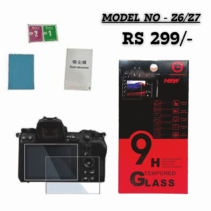 On the left, there is a Nikon Z-series mirrorless camera (likely a Z6 or Z7) shown with the tempered glass screen protector applied to its main LCD screen, and an extra small protector for the top display. Next to the camera are the included installation accessories: a blue microfiber cloth, and two small packets labeled with numbers (likely wet/dry wipes) and a "Dust-absorber" sticker.