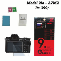High-resolution image of a complete camera screen protector kit, featuring the 9H Tempered Glass box (red and black), the model number A7M2, and the price Rs 399/-. The kit includes the glass protector positioned on a camera screen, a blue microfiber cloth, and wet/dry cleaning wipes. The packaging highlights features like 9H Hardness, Explosion proof, and Bubble-Free installation.