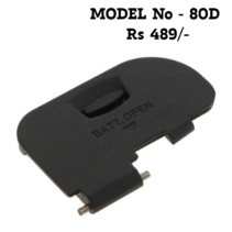 Replacement battery door cover for Canon EOS 80D camera showing the internal spring mechanism and "BATT. OPEN" latch.